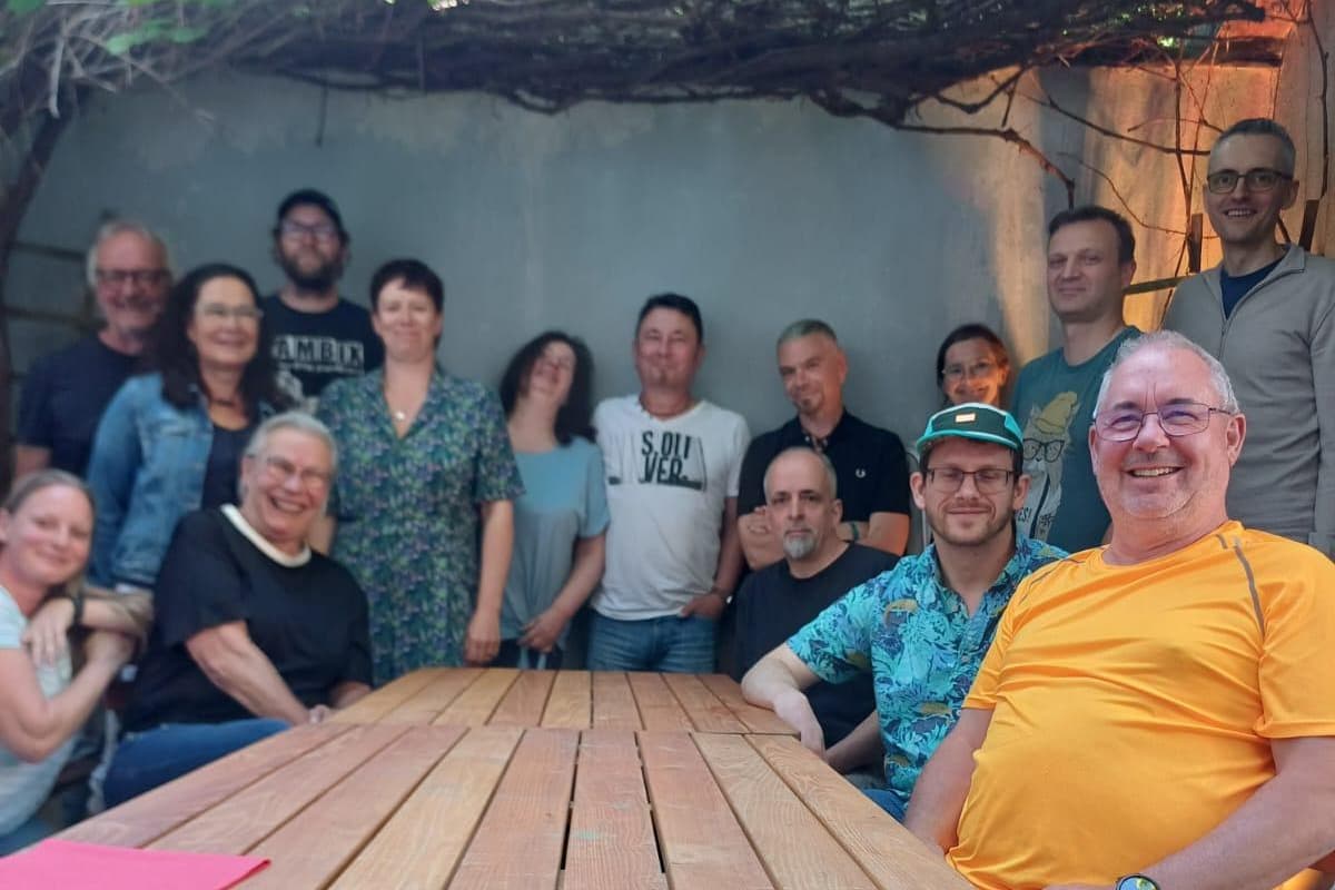 Foto von der Vereinssitzung zur Entscheidung über Ring on Feier 2025. 15 Personen sitzen und stehen bei sommerlichen Temperaturen in einem Garten um einen großen Tisch.